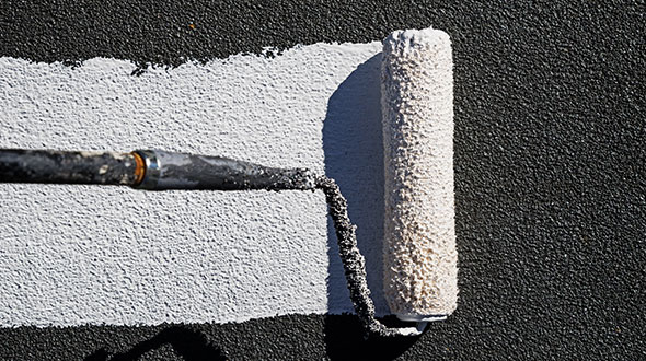 Commercial roof coating being applied with a roller on a flat roofing system