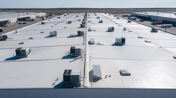 large warehouse featuring a flat commercial roof with visible HVAC equipment