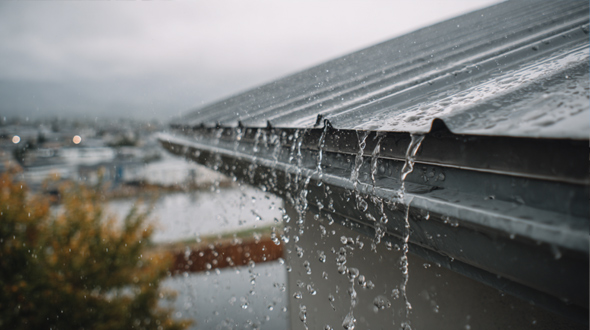 metal roof with water sheeting off its surface during a heavy rainfall