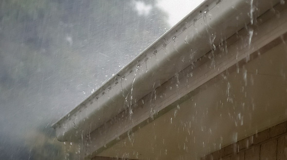 Rain gutters and commercial roofing system damaged in severe weather