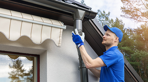 roofing professional installing seamless metal gutters on a metal roof, ensuring proper drainage